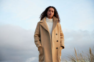 Camel wool coat over a cream roll-neck, styled on the coast